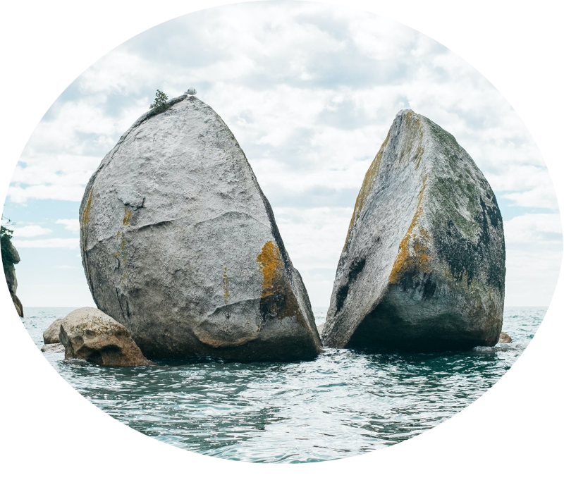 a large round boulder in the ocean split down the middle